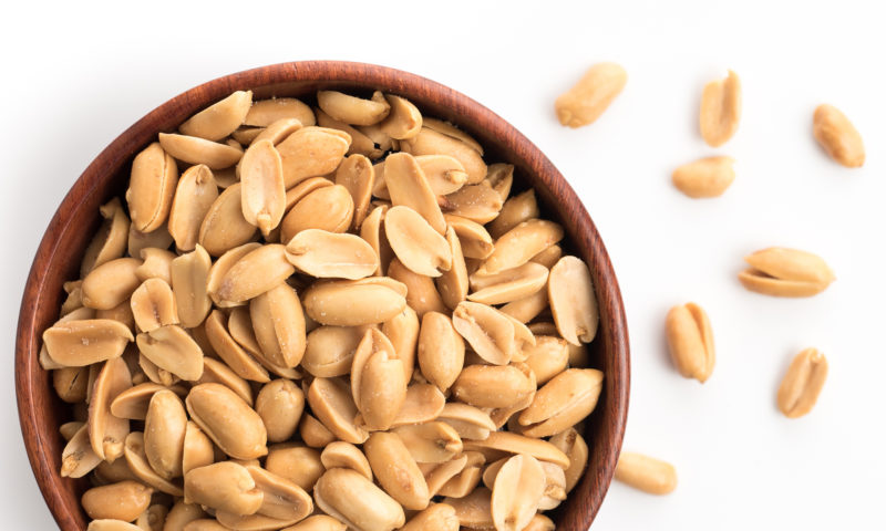 Roasted salted peanuts in wooden bowl on white background,top vi