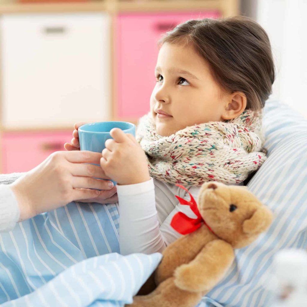 mother giving hot tea to sick little daughter