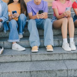 Cropped picture of group teenagers holding mobile phones watchin